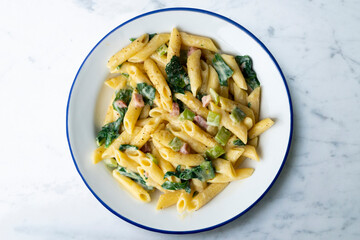 Italian macaroni with chard, ham and cream sauce. Top view table with  decorations.