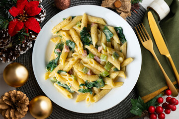 Italian macaroni with chard, ham and cream sauce. Top view table with Christmas decorations.