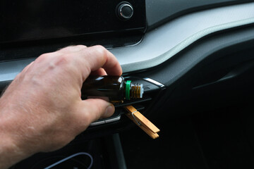 Installation of a clothespin on a car interior vent, impregnated with essential oil. To detoxify and remove unpleasant odours.