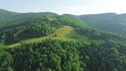 Scenic aerial view of forested mountains with clear blue sky and clouds