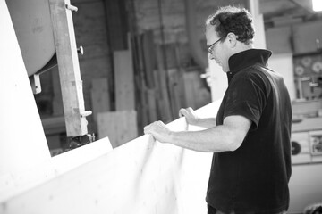 Carpenter working on a wood panel in his workshop. - black n whi