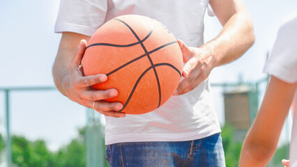 Active young male playing street basketball, dribbling ball, training on court