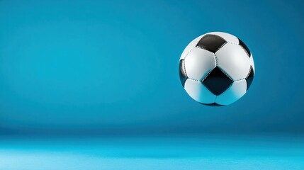 Naklejka premium Soccer ball floating mid-air against a vibrant blue background emphasizing the simplicity and energy of the sport