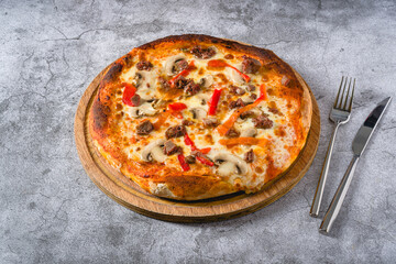 Pizza with paprika and roast beef on cutting board on stone table