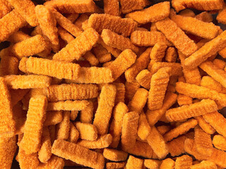Fish fingers. Frozen breaded orange fish fingers sticks in the market fridge as a background.