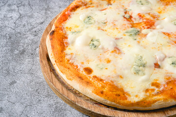 Four cheese neapolitan pizza on wooden cutting board on stone table