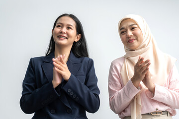 Two businesswomen in formal attire smiling and clapping during a corporate meeting, celebrating success and achievements, diverse workplace environment with professional women engaged in teamwork