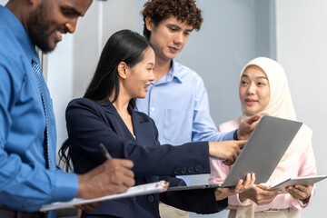 Diverse group of business professionals in formal collaborating during a corporate meeting, focused on technology and teamwork, asian businesswoman leading with laptop, teamwork and collaboration