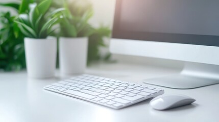 Fototapeta premium Modern workspace with a computer, keyboard, and green plants on a bright desk.