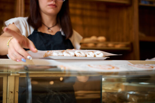 Woman selecting fresh pastries at a bakery in the late morning hours