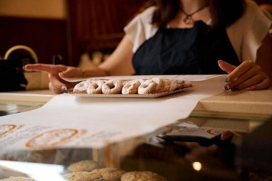 Woman selecting fresh pastries at a bakery in the late morning hours