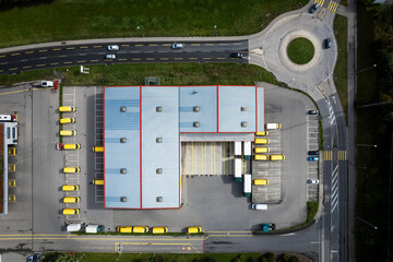 Vue aérienne d'un dépôt avec des véhicules jaune et blanc parqué autour.