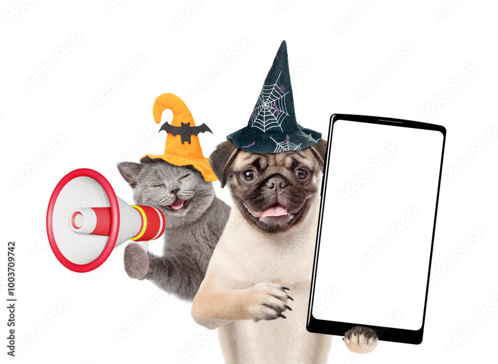 Poster happy cat and pug puppy wearing hats for halloween looks at camera. dog shows smartphone with white 