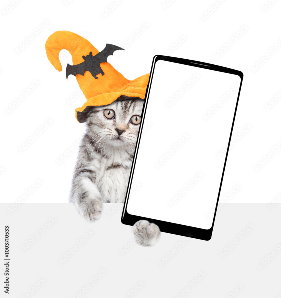 Aufkleber cute kitten wearing hat for halloween holds shows smartphone with white blank screen in it paw above