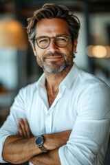 Confident and handsome businessman in a white shirt smiling with arms crossed in a modern office setting