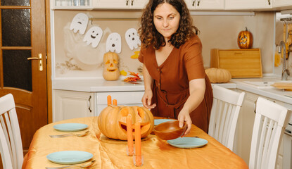 A middle-aged woman sets the table for the Halloween party
