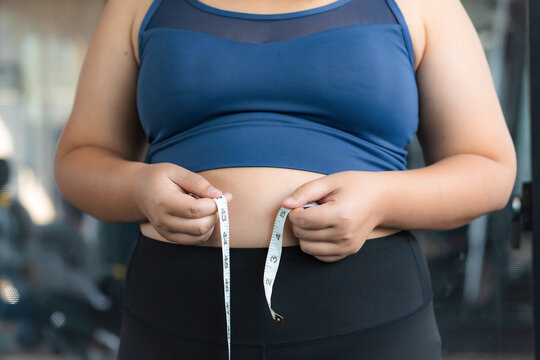 Chubby obese woman check out body fat with measuring tape health care diet lifestyle concept