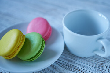 Colorful macaroons on a white plate and a cup of coffee