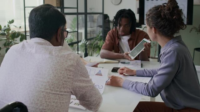 Multiethnic team meeting at office to test new financial app