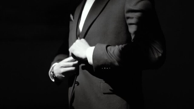 A handsome male businessman in a jacket and suit buttons up his clothes. Morning of the groom before the wedding ceremony and meeting the bride