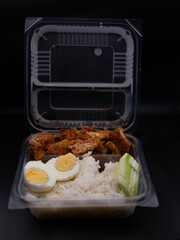 Spicy chicken rice salad with boiled eggs put in a clear plastic box.