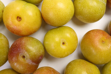 Ripe sweet small mini plum green maroon on white background