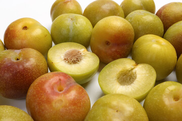 Ripe sweet small mini plum green maroon on white background