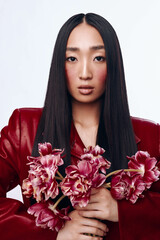 Elegant woman with long black hair and red jacket holding a beautiful bouquet of flowers at outdoor event