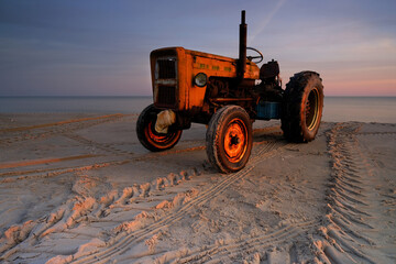 Stary traktor na bałtyckiej plaży, w  śwetle wschodzącego słońca