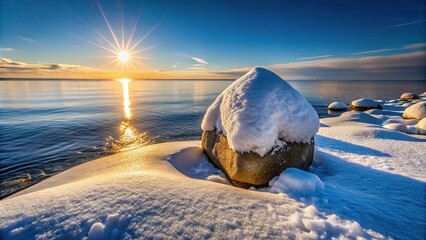 Large icy stone on seashore with snow against sea and sun