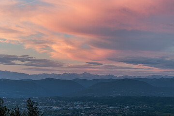 vista da lontano di varie catene di montagne che si estendono verso l'orizzonte, tra Italia e Slovenia, durante un bellissimo tramonto colorato, con cielo nuvoloso, in estate