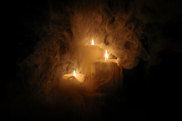 Lit candle flame through heavy smoke fog mist vapour flow twist beautiful mistic