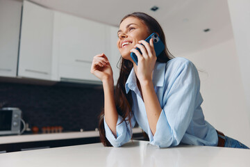 Busy woman talking on phone at table in contemporary kitchen interior