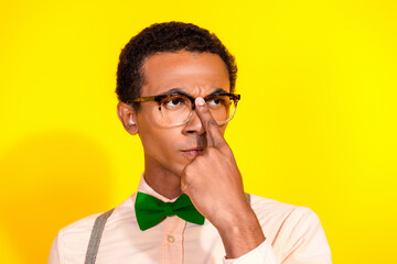Photo of elegant young man fix eyeglasses look empty space wear shirt bow tie isolated on yellow...