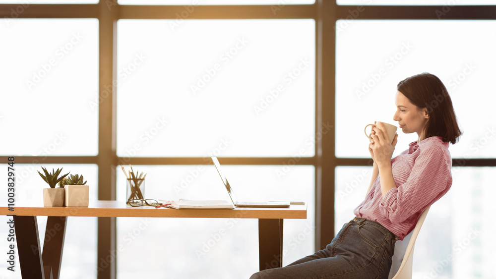 Poster watching tutorial. side view portrait of happy casual girl sitting at table, drinking hot coffee and