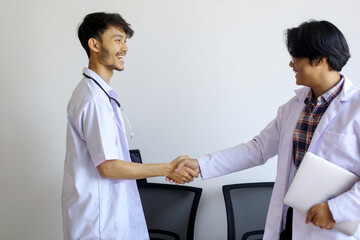 Obraz premium Two Asian Medical Students Shaking Hands At Hospital