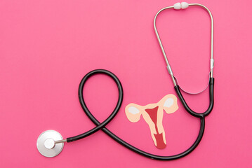 Fototapeta premium Stethoscope and paper uterus on Vibrant Pink Background for Gynecological Care
