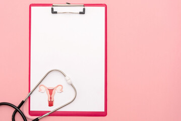 Clipboard with Stethoscope Framing a Paper Cutout uterus on pink background,women's health and...