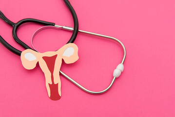 close up of Stethoscope and paper uterus on vibrant pink background, women's Gynecology health Concept