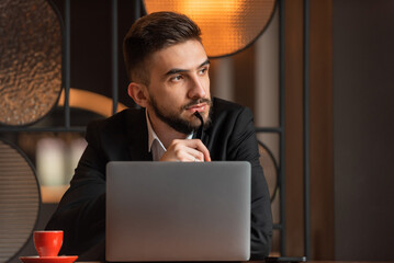 A young business man looking away and thinking in the office.
