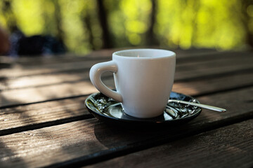 primo piano da vicino di una tazza di caffè bianca su un piatto nero appoggiata su un tavolo di...