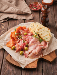 A delicious charcuterie board featuring assorted cured meats, olives, fresh bread, and crispy snacks set in a rustic kitchen