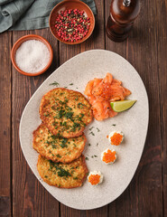 Delicious potato pancakes served with smoked salmon and garnishes on a rustic wooden table
