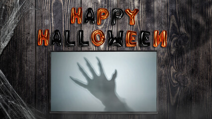 Shade of werewolf hands with fur and black claws on the screen with Happy Halloween balloon text on...