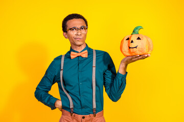 Photo of unsure guy hold halloween pumpkin vegetable hesitating isolated bright color background