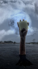 Zombie hand with bloody wound rising out of ground holding notes paper. Blank notes paper for copy...