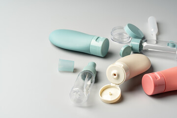 Collection of various reusable cosmetic containers arranged on a light gray background