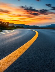Naklejka premium Curvy road under a vibrant sunset sky with mountains in the background.