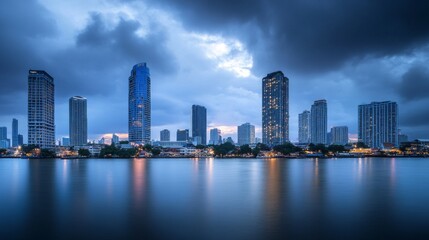 Fototapeta premium Skyline of modern Bangkok, Thailand. Majestic skyscrapers on the waterfront under the cloudy sky at twilight time.