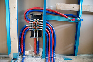 construction site, collection of black corrugated pipes arranged to follow a curved path, used for the electrical system in a rough brick wall